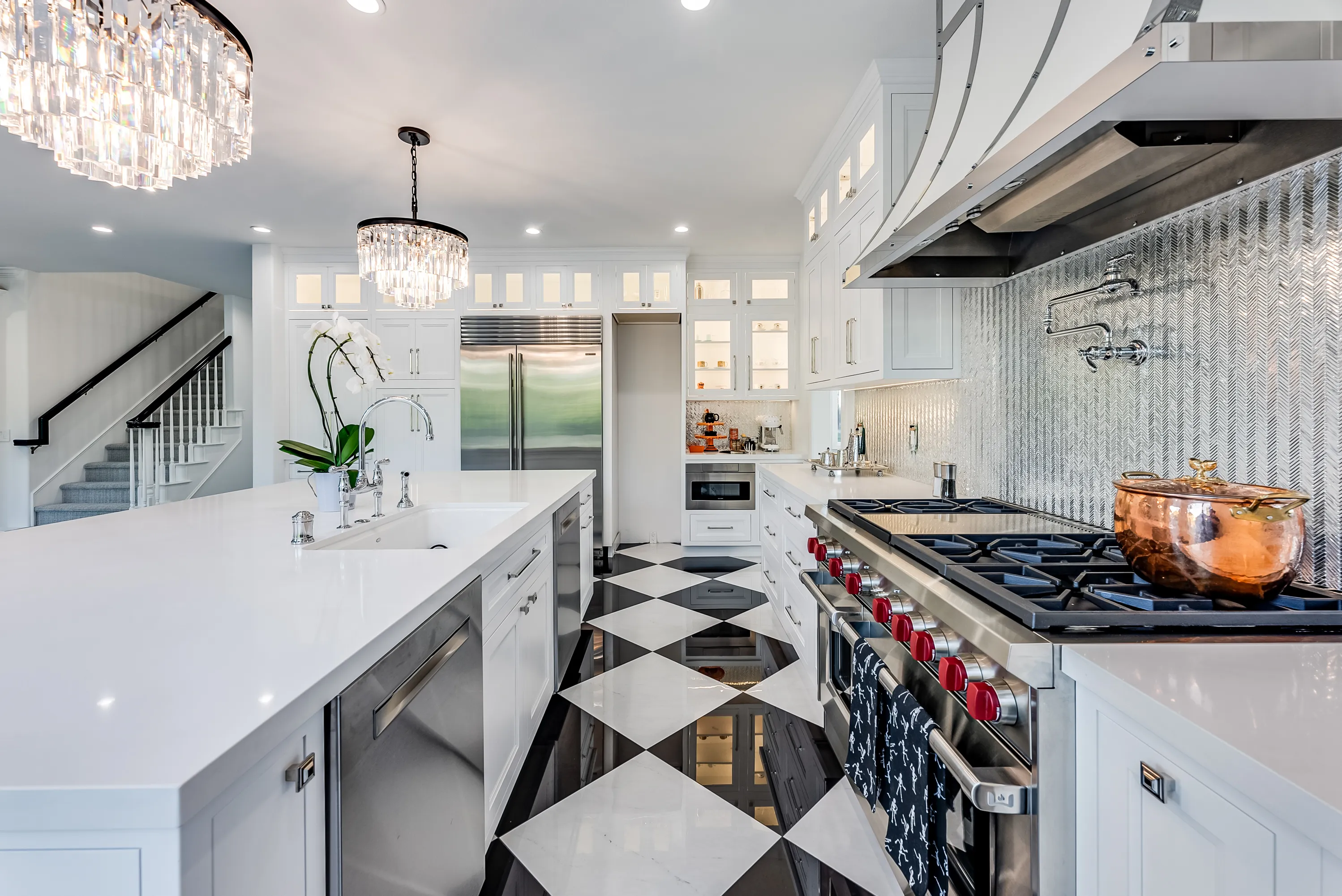 Kitchen overview with island, chandeliers and range wall