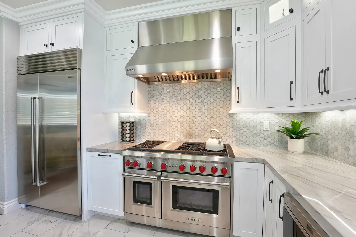 Professional range with stainless hood beside a built-in refrigerator
