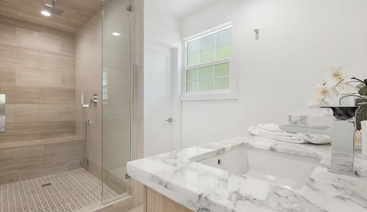 Walk-in shower with wood-look tile, built-in bench and marble vanity