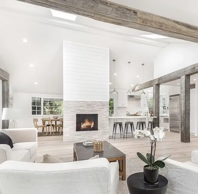 Open great room with fireplace, dining area and kitchen under reclaimed beams in Lake Sherwood