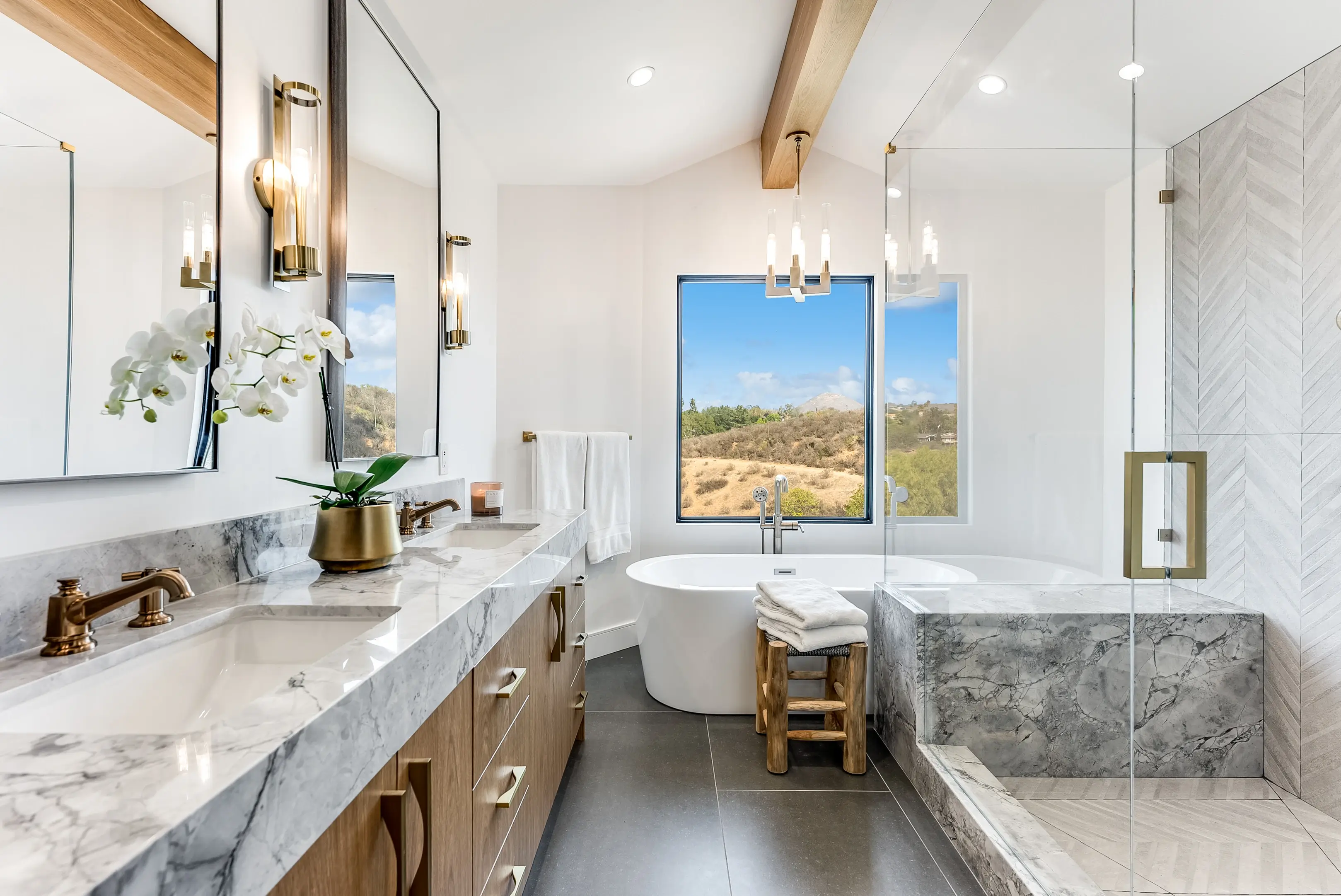 Primary bathroom with double vanity, tub and glass shower
