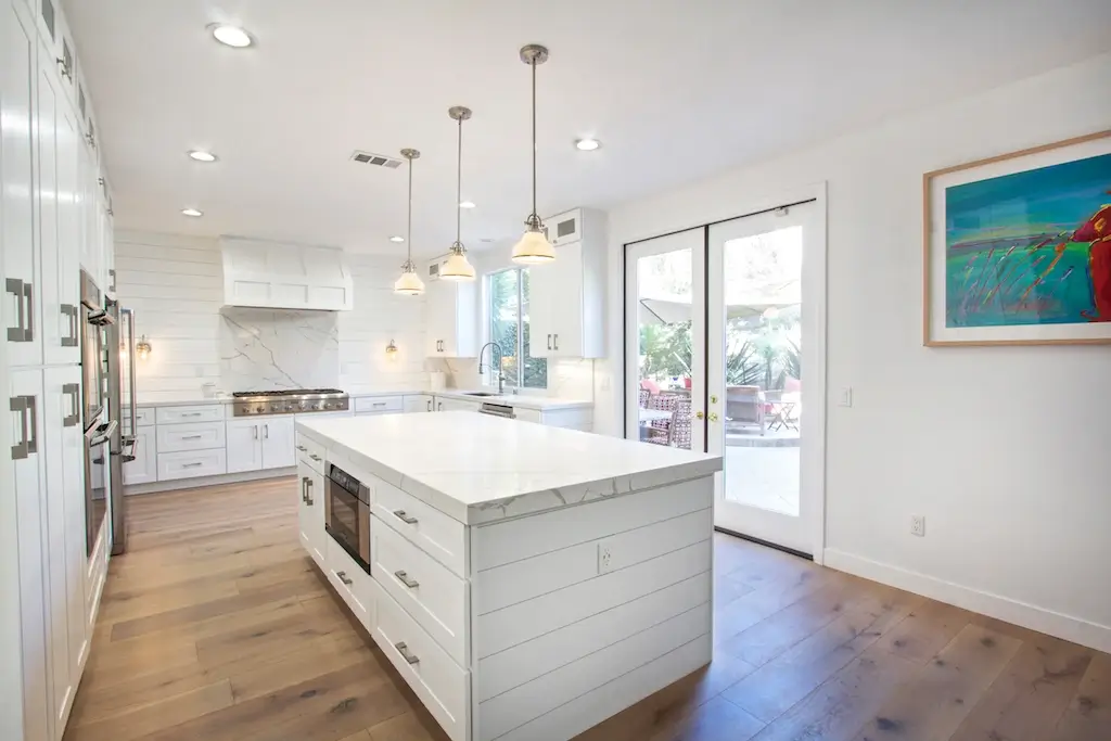 White kitchen with long marble island and glass pendants in Lynn Ranch