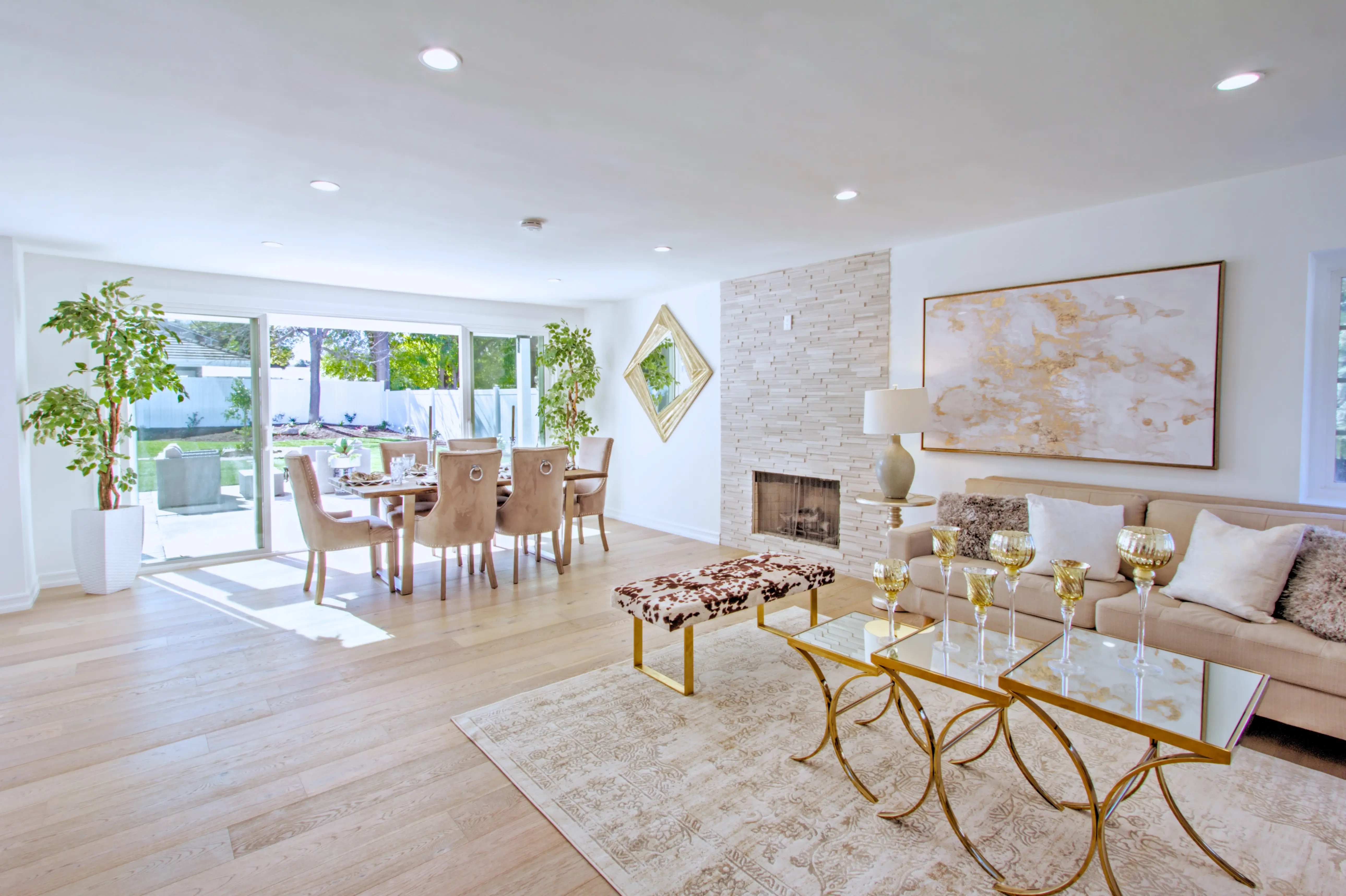Open living and dining room with oak floors and stone fireplace wall