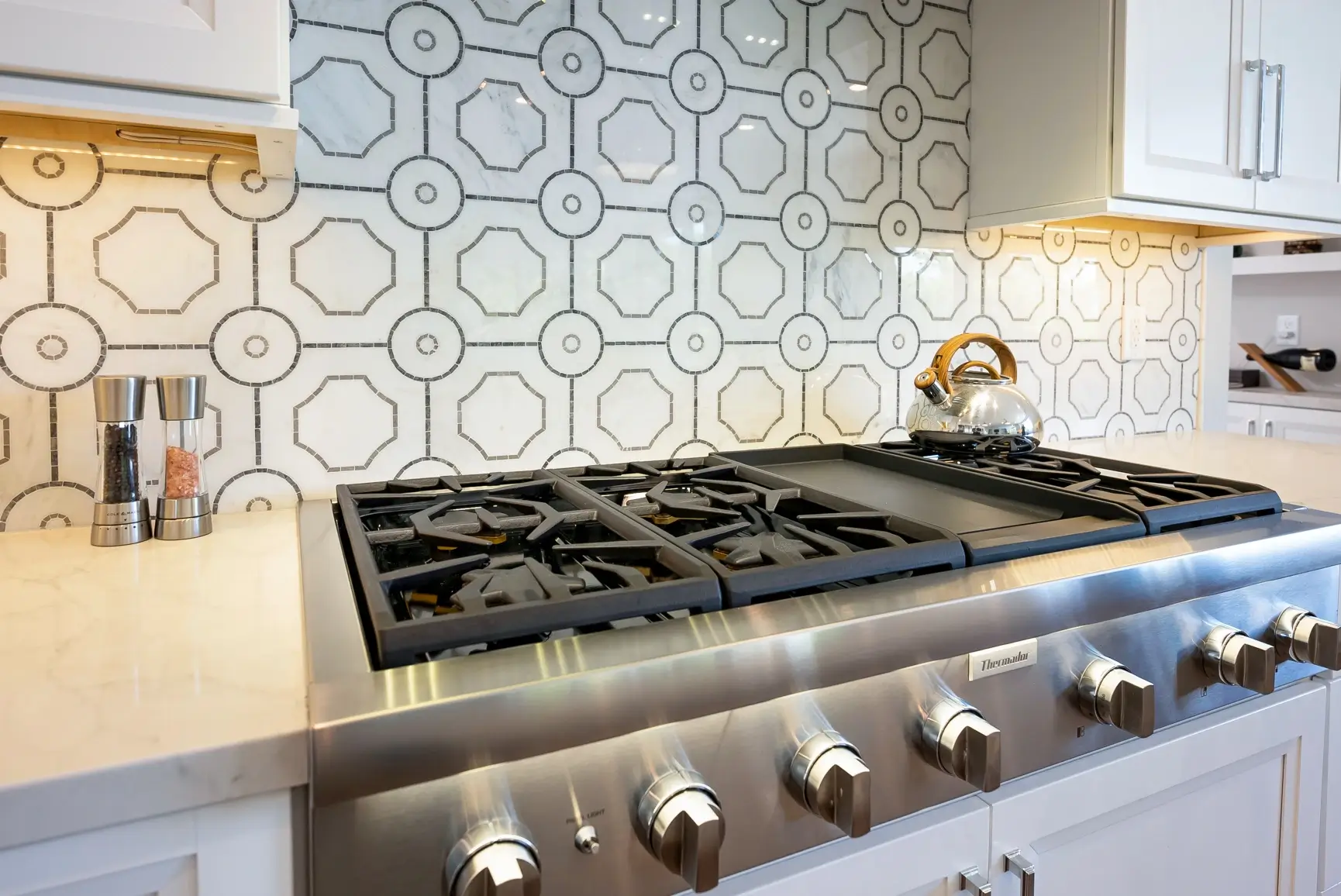 Geometric tile backsplash behind the gas cooktop
